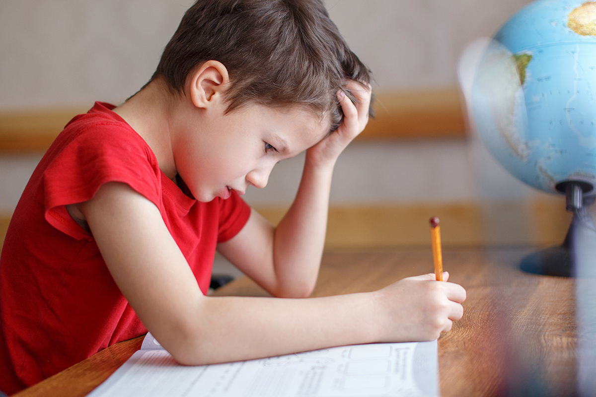 Sad little boy depressed while doing homework